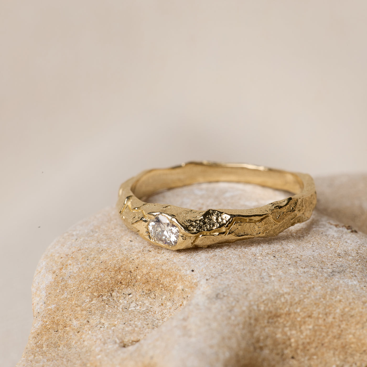 Bespoke organic gold cuff bracelet with raw diamond clusters on sandstone