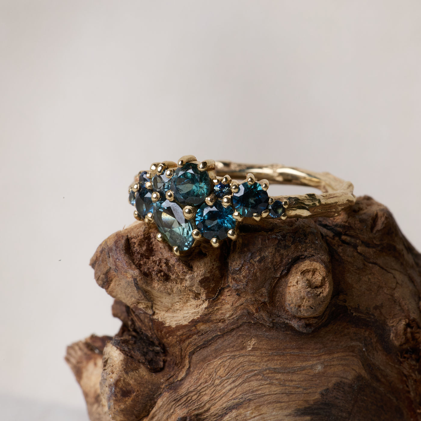 Bespoke organic gold earrings with raw sapphire clusters on driftwood