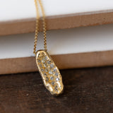 Raw oblong concave pendant with white diamonds